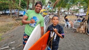Jeremias Reyes (licra negra) de 10 años dio una gran demostración de talento y valentía en la categoría Boys, al enfrentarse a las retadoras condiciones de playa hermosa. Aquí vemos a Jeremías junto a su coach Ariel Gutierrez.